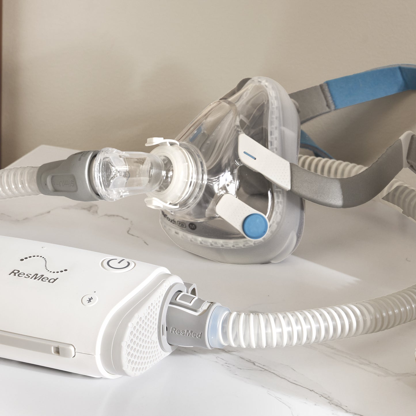 ResMed CPAP machine with mask and hose on a white surface