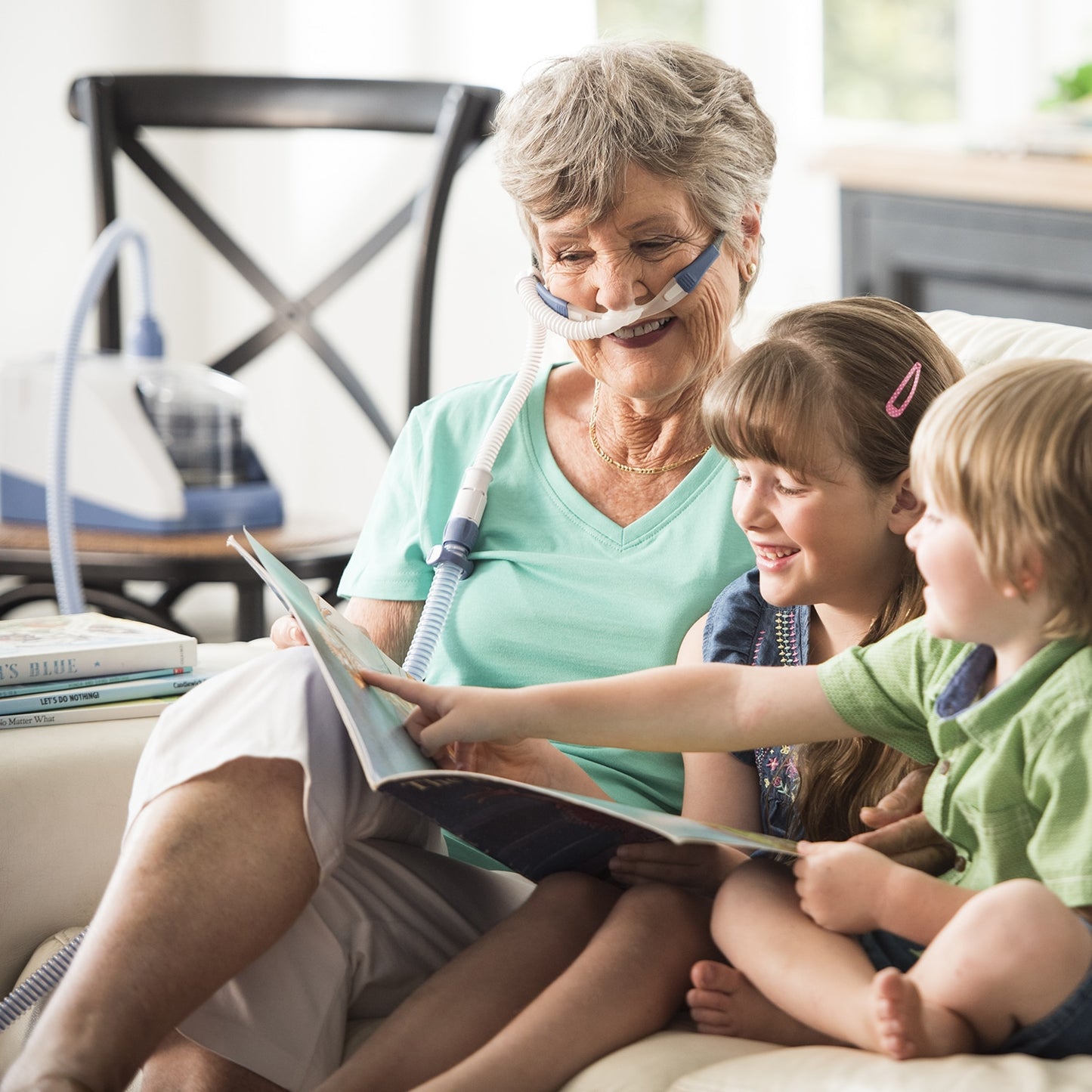 Woman with a oxygen mask reading to two children in a home setting