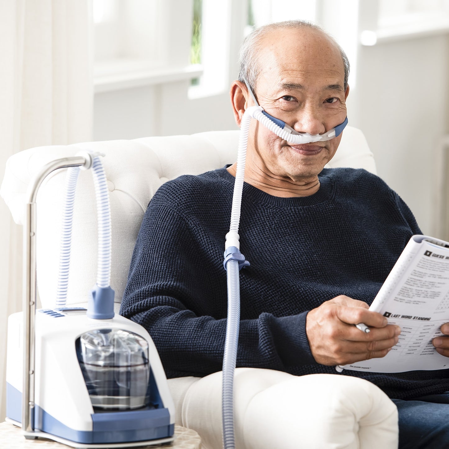Man wearing CPAP Mask while sitting in a chair reading