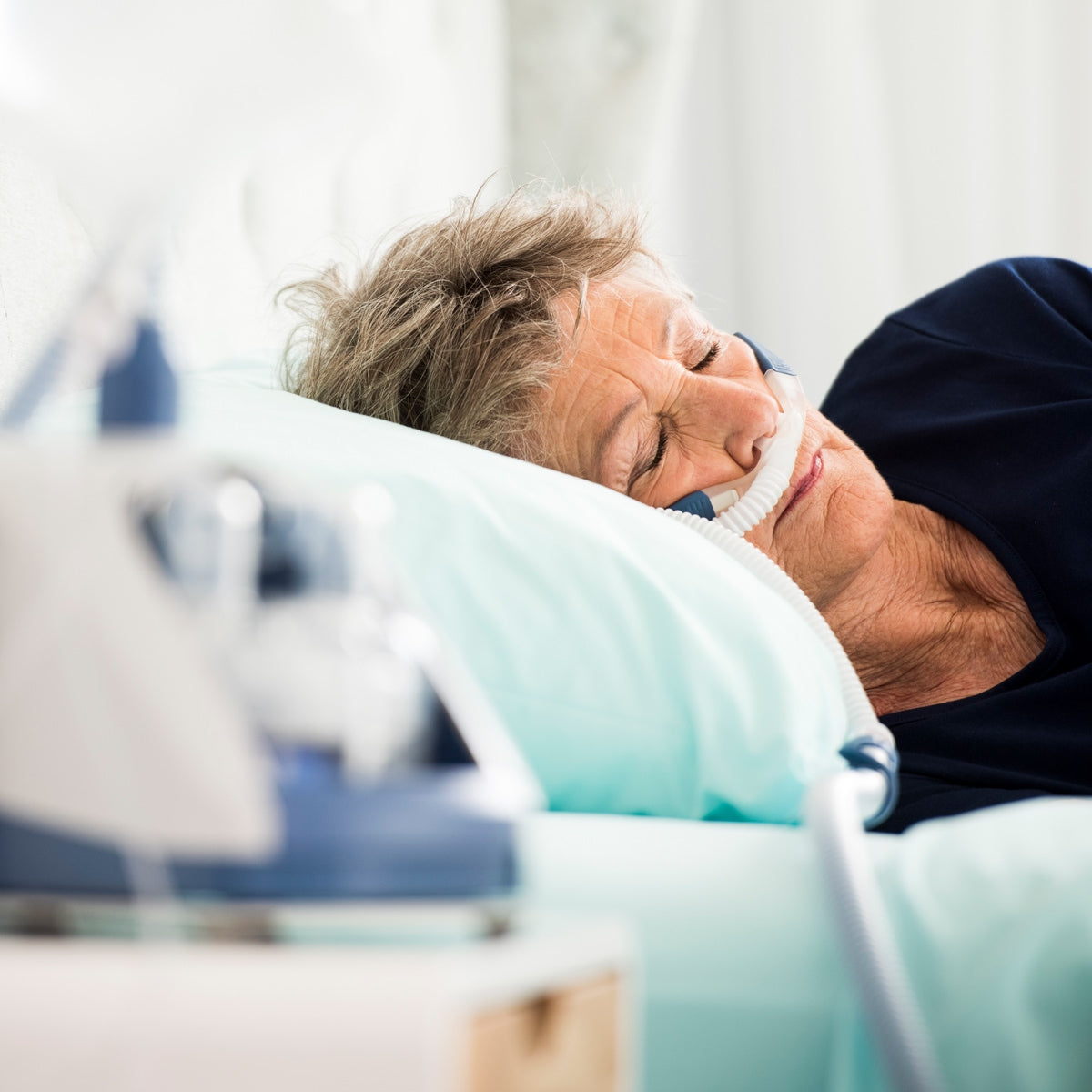 Woman in bed sleeping using a CPAP Mask