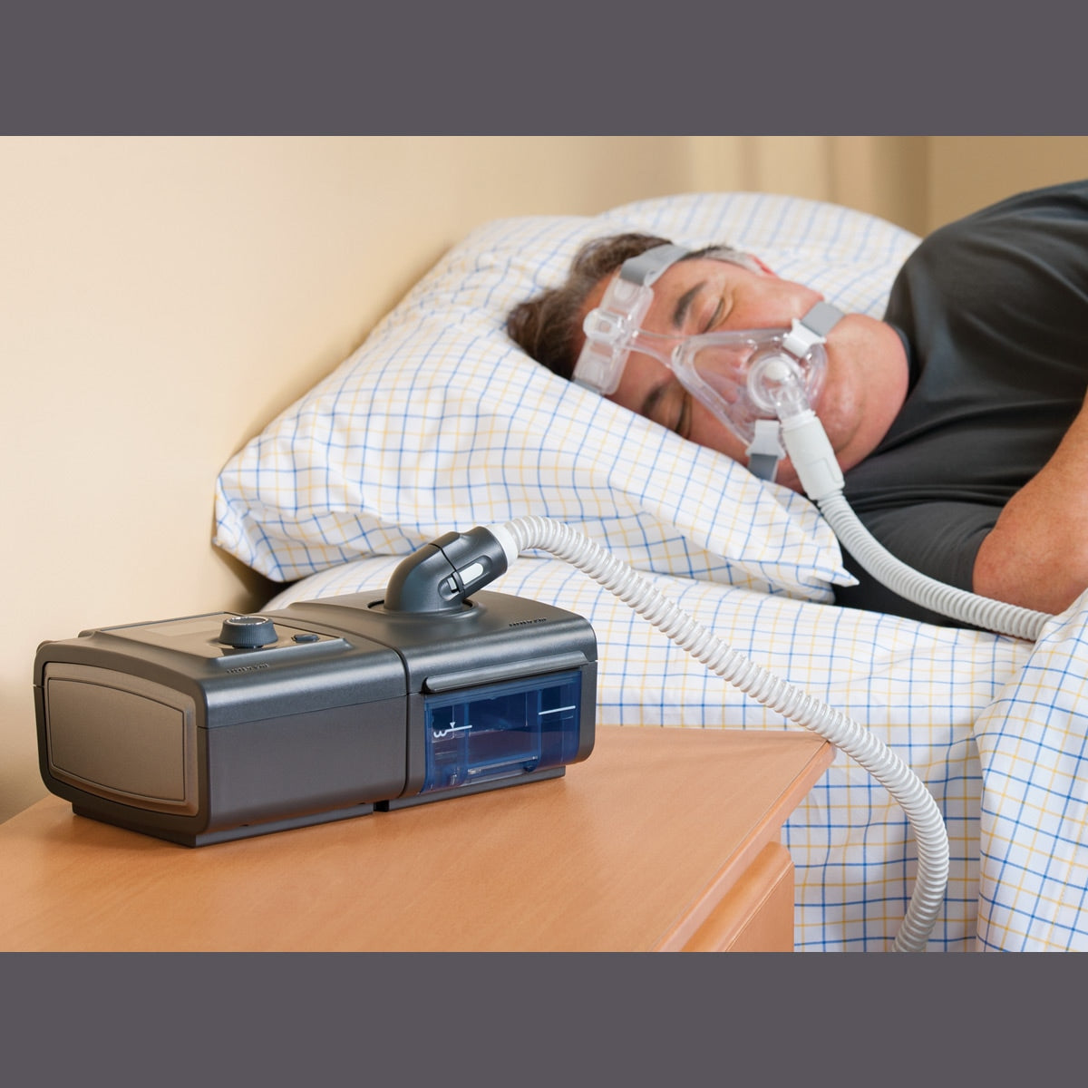 Man in Bed wearing CPAP Mask with System Once CPAP Machine on Side Table