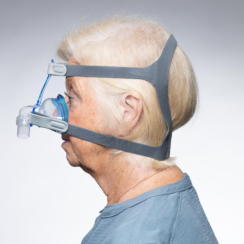 Person wearing a CPAP mask on a plain background
