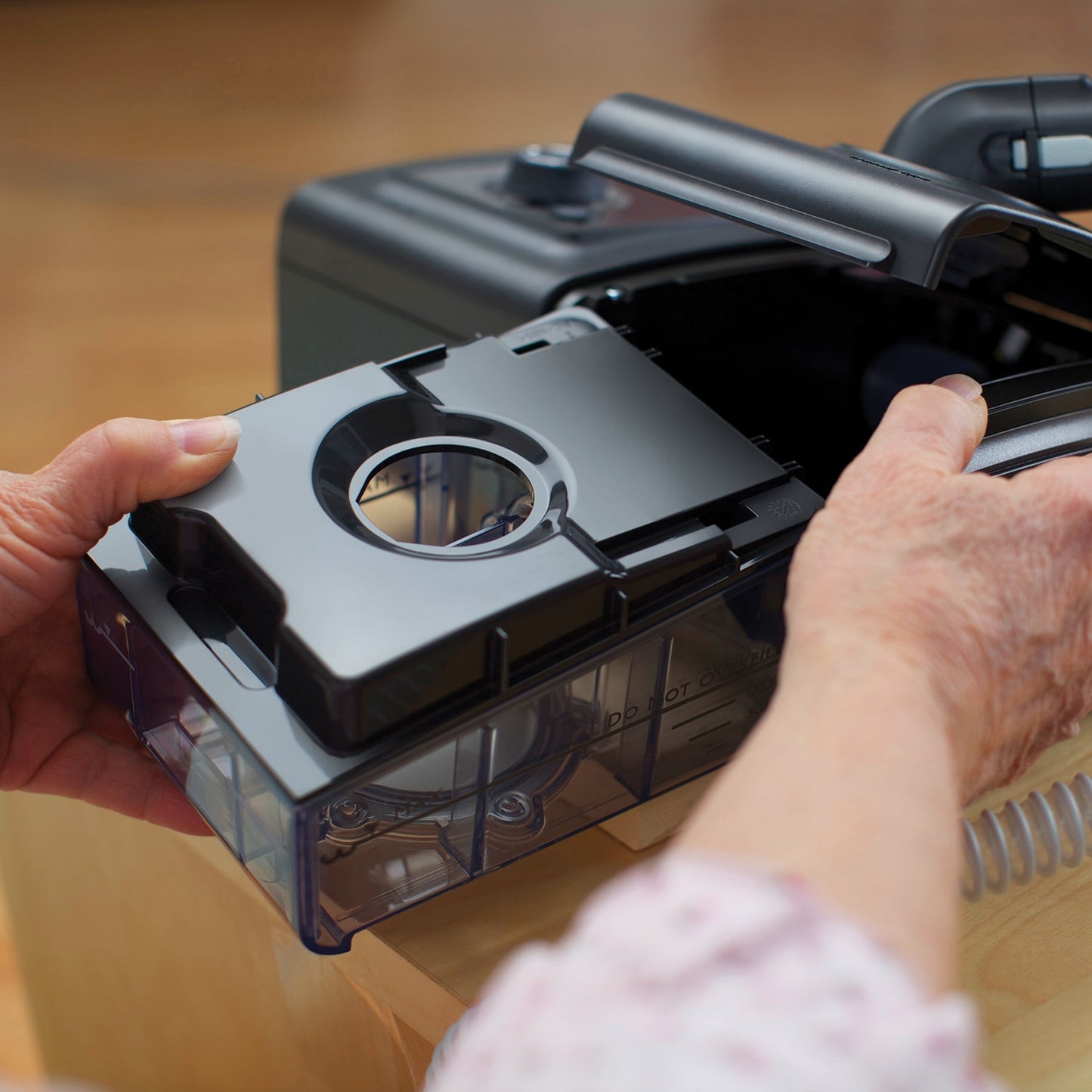 Hands inserting a humidifier chamber into System One CPAP
