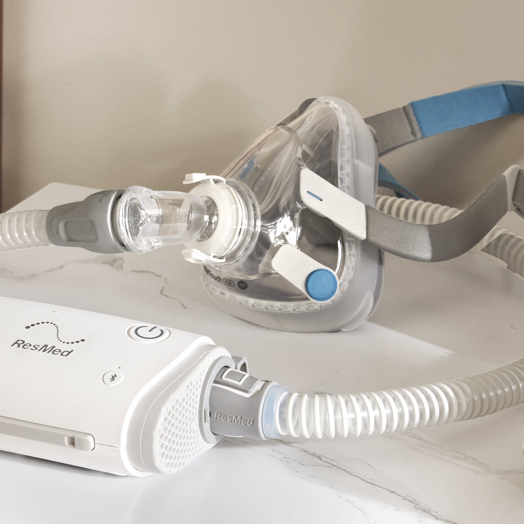 ResMed CPAP machine with mask and hose on a white surface