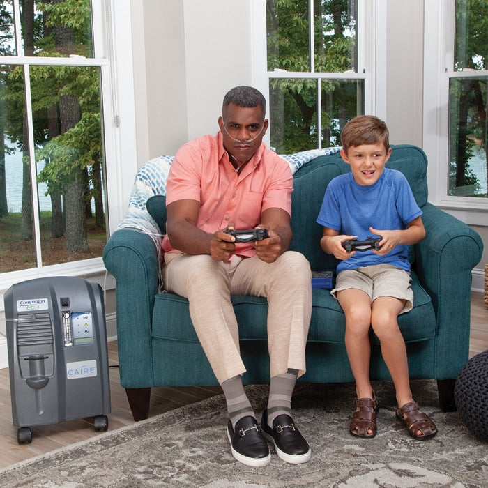 Man playing video games with child while wearing Companion Oxygen Concentrator 