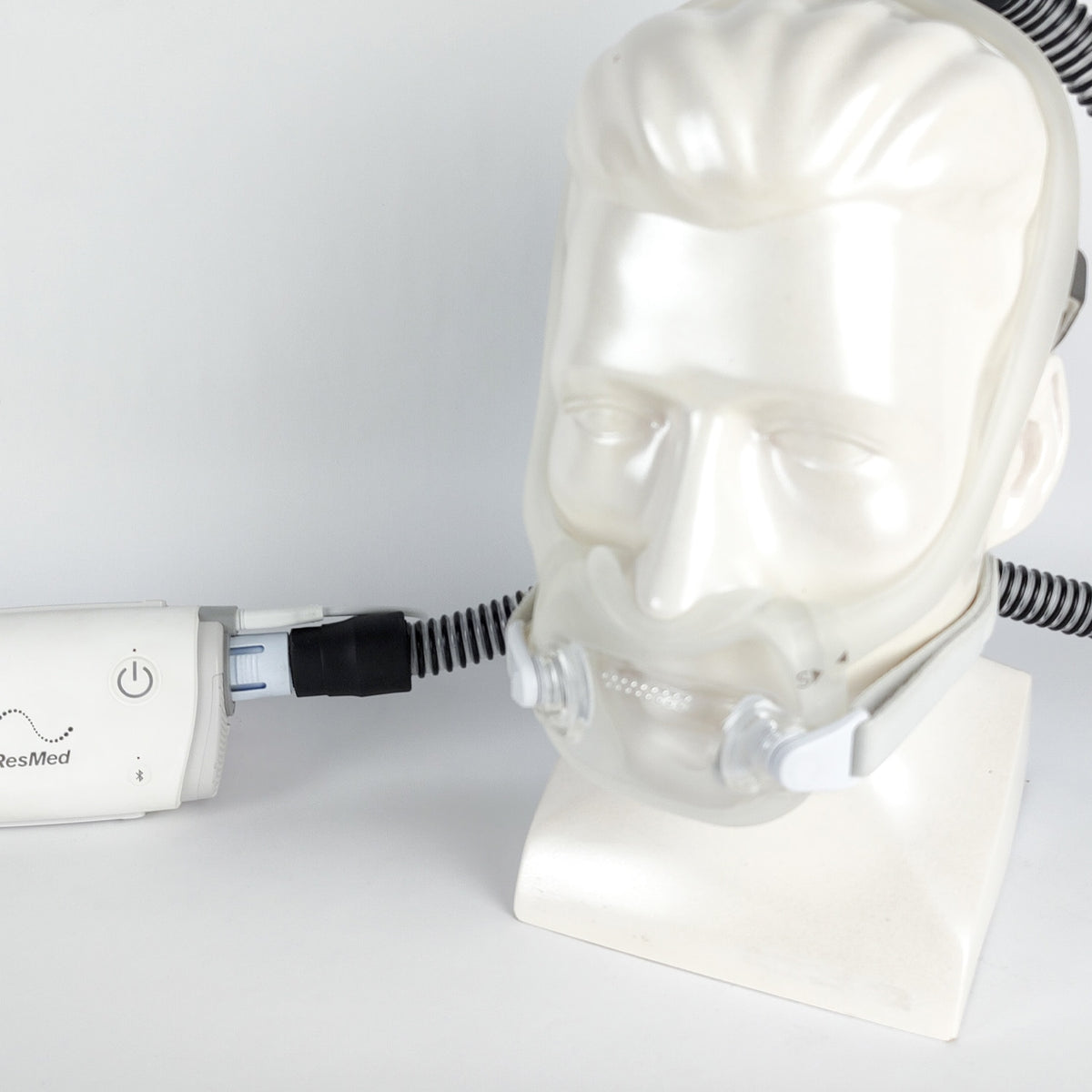 CPAP machine and mask on a mannequin head with a white background