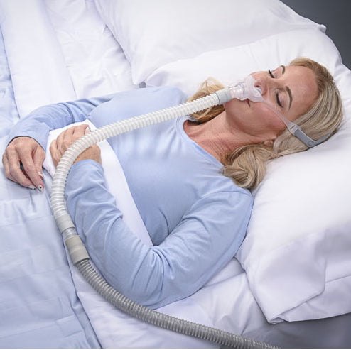 Woman using a CPAP machine while sleeping in bed