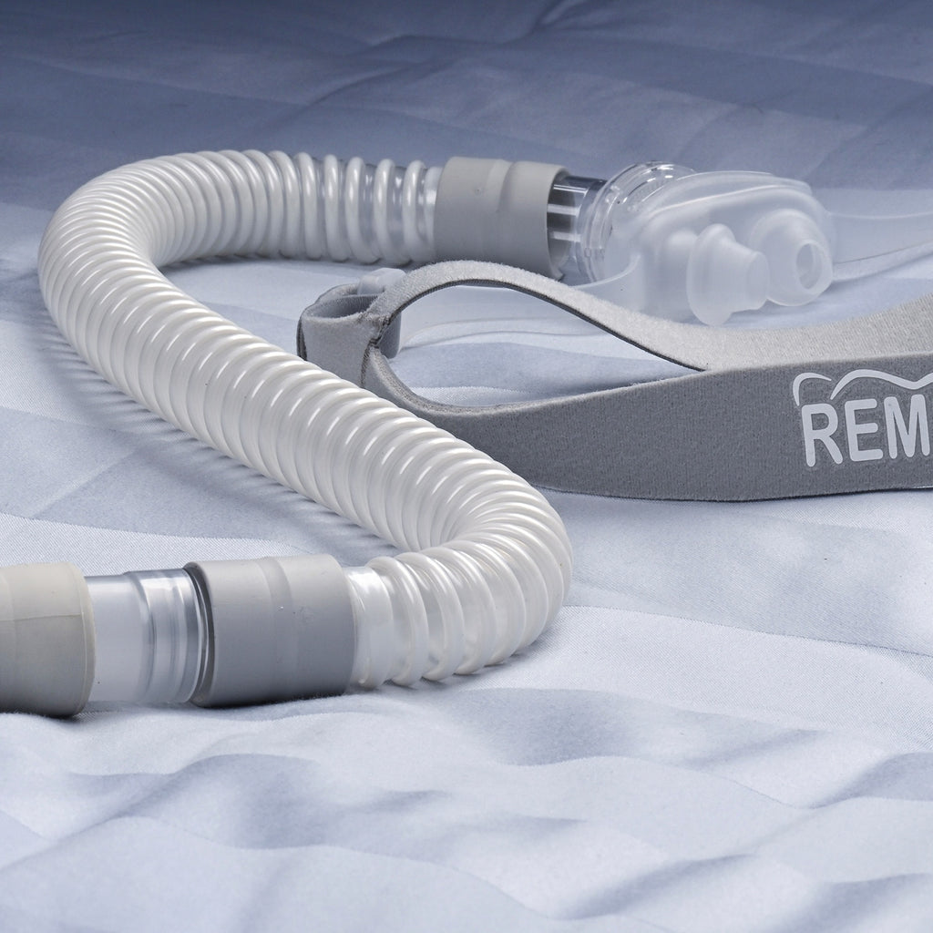 CPAP hose and mask on a textured surface with 'REM' branding.