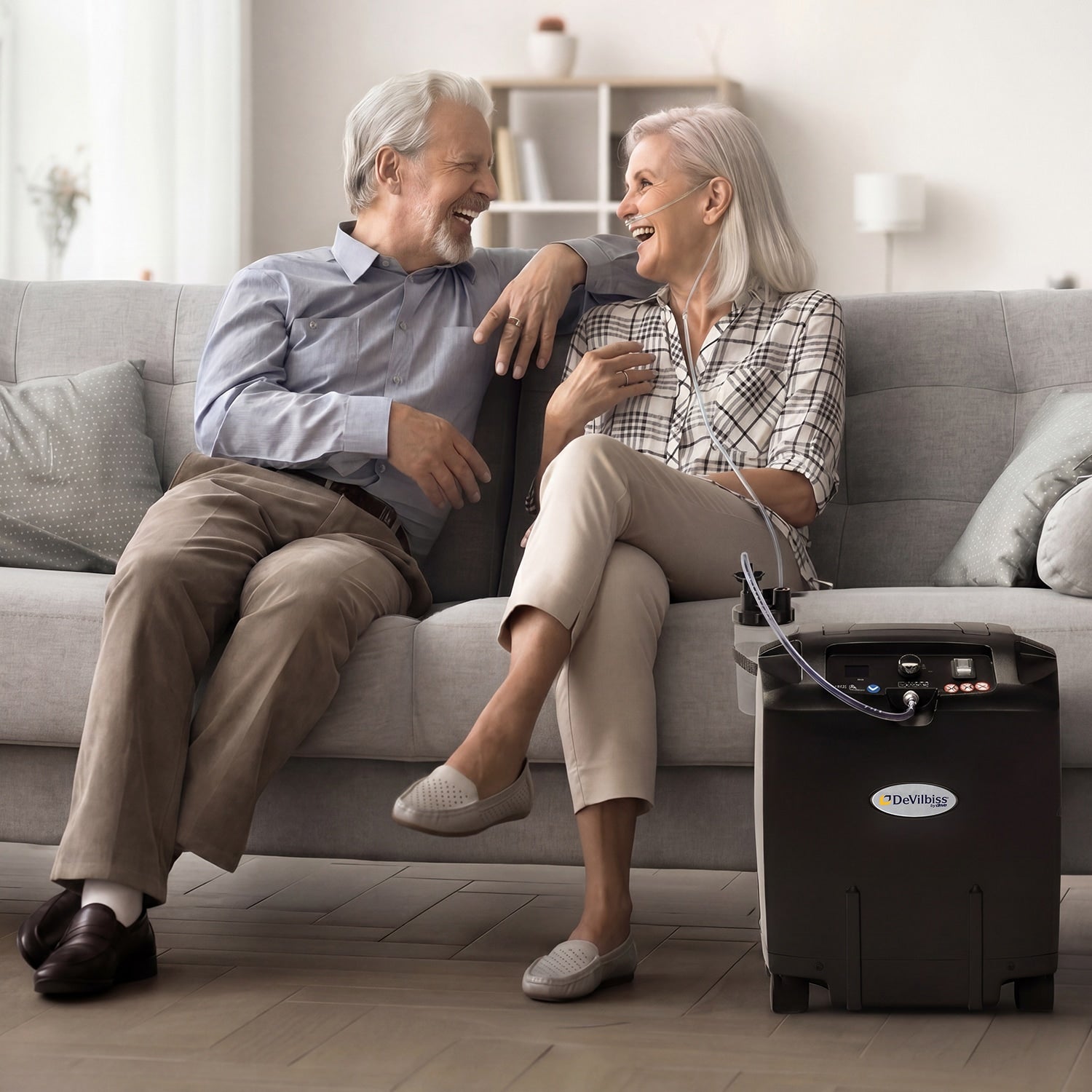 Senior couple sitting on a couch with a portable air conditioner in front of them.
