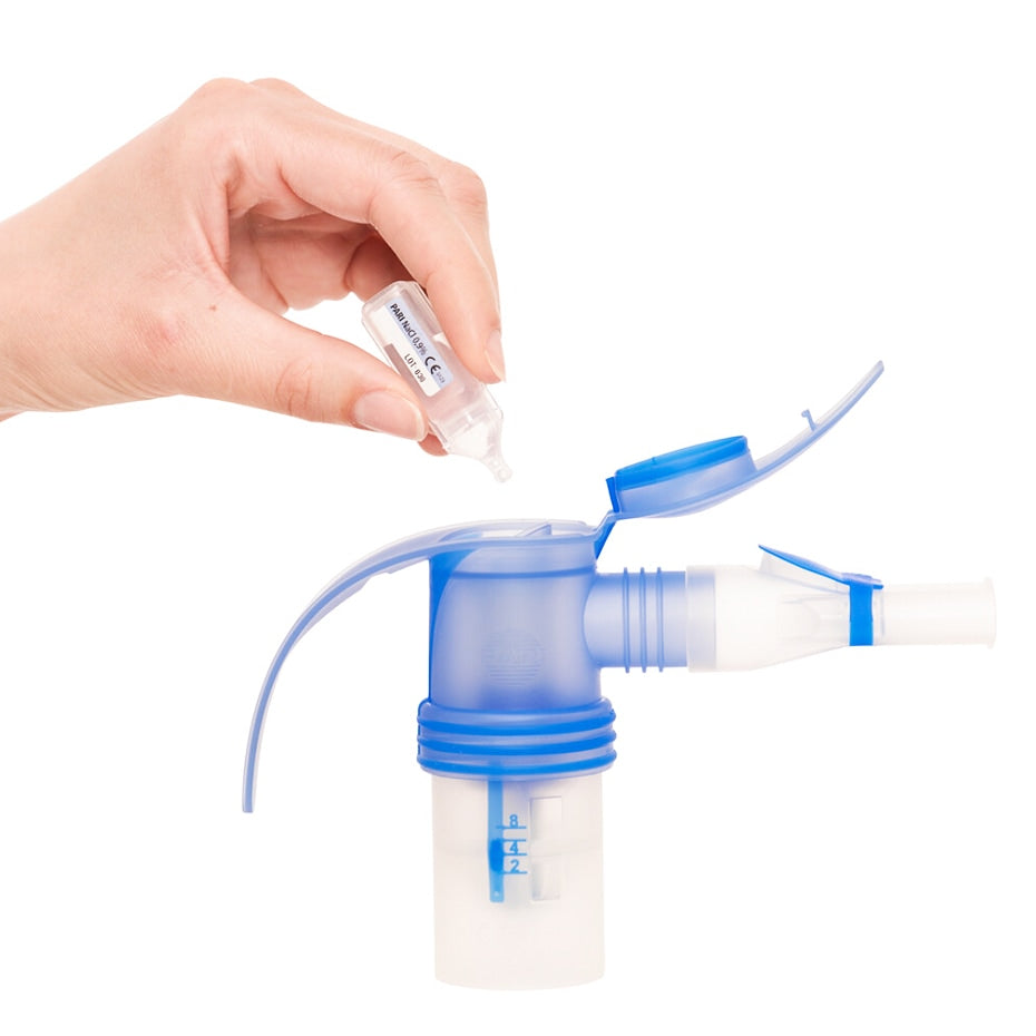 Hand holding a small container of medicine over pari lc sprint nebulizer on a white background