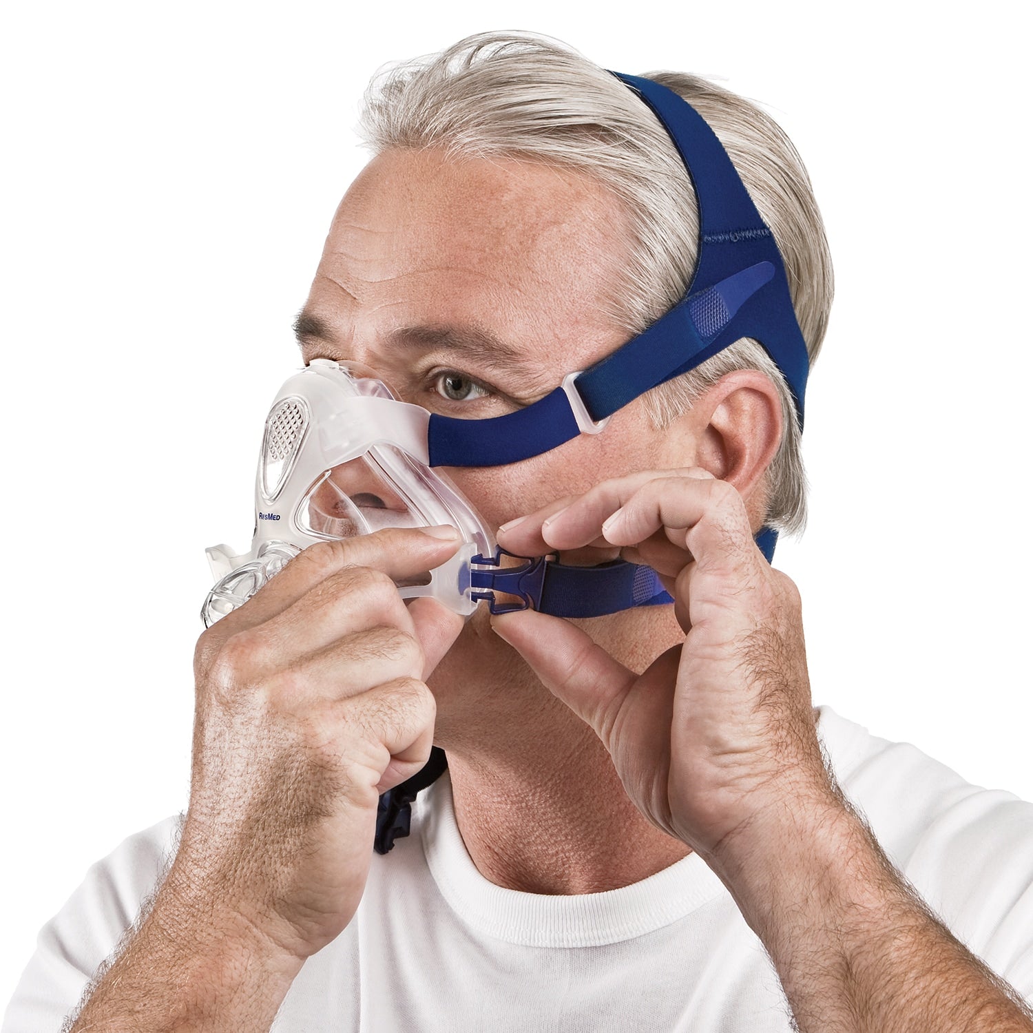 Man wearing a blue and white CPAP mask on a white background
