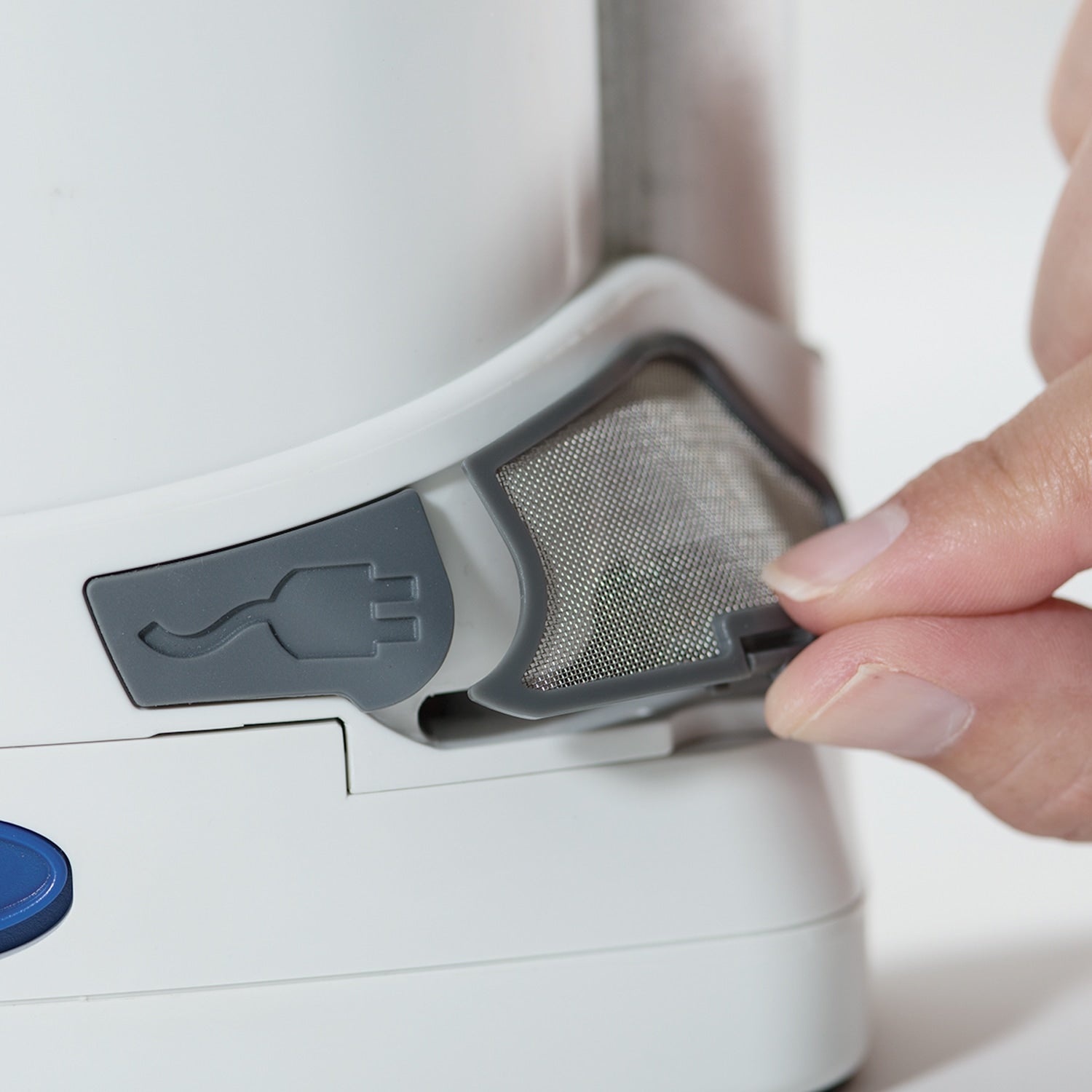 Person replacing a filter in a white freestyle comfort with a gray mesh filter