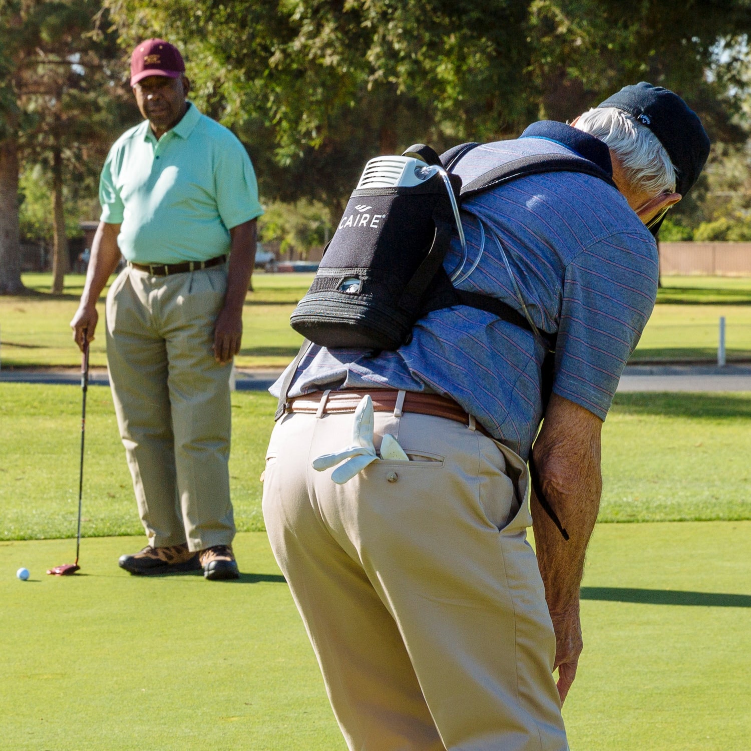 Person on a golf course wearing a back backpack with a freestyle comfort portable concentrator 