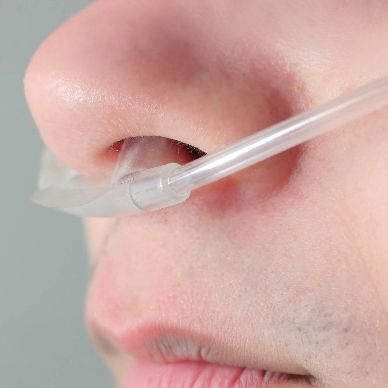 Person wearing a nasal cannula on a gray background