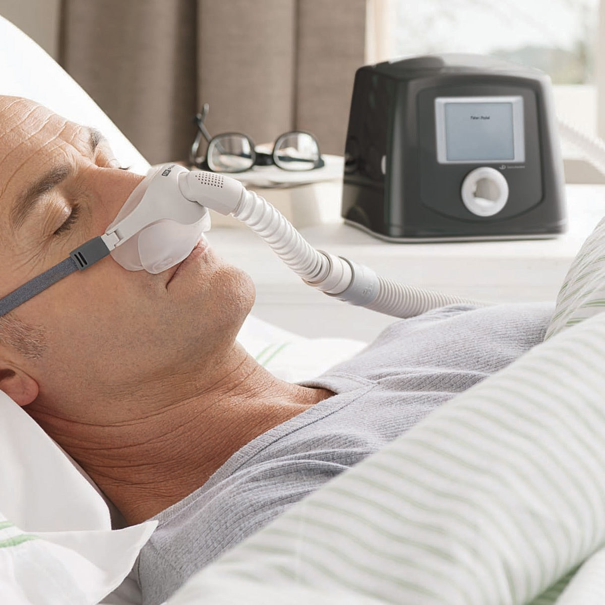 Man Wearing CPAP Mask in Bed with Icon Plus Machine on Side Table 