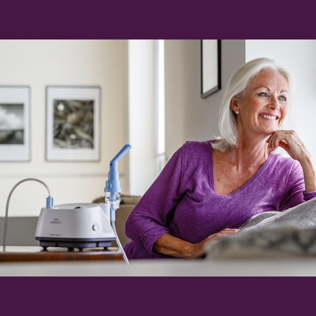 Inspire Elegance Compressor Nebulizer on table with lady sitting next to it 