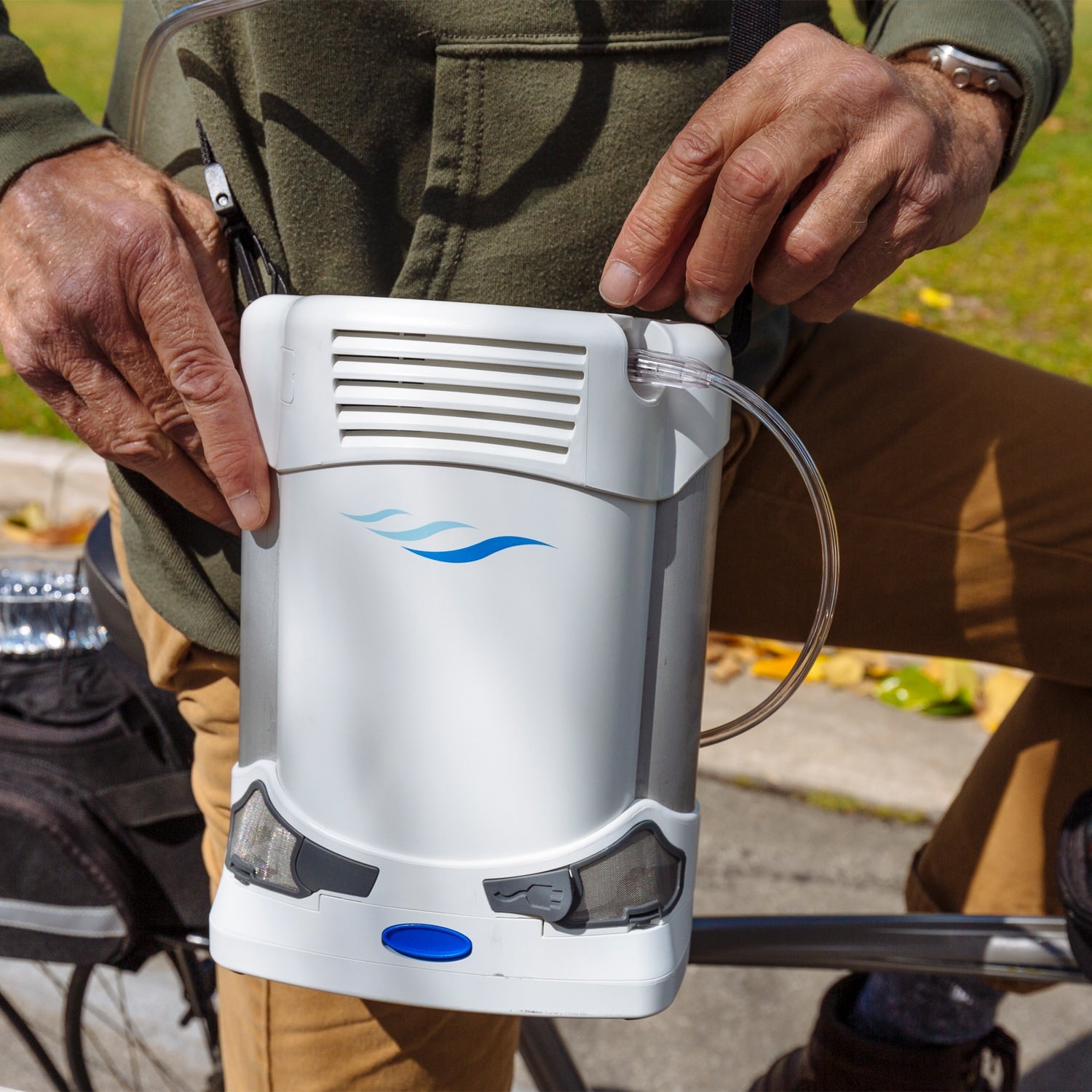 Person holding a white handheld device with a blue logo outdoors