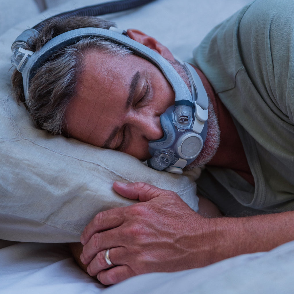 Man sleeping with a CPAP mask on in bed