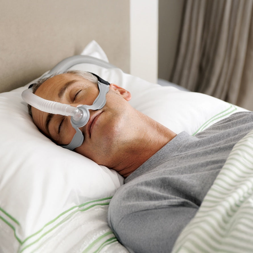 Person sleeping with an Opus 360 CPAP mask on in a bedroom setting