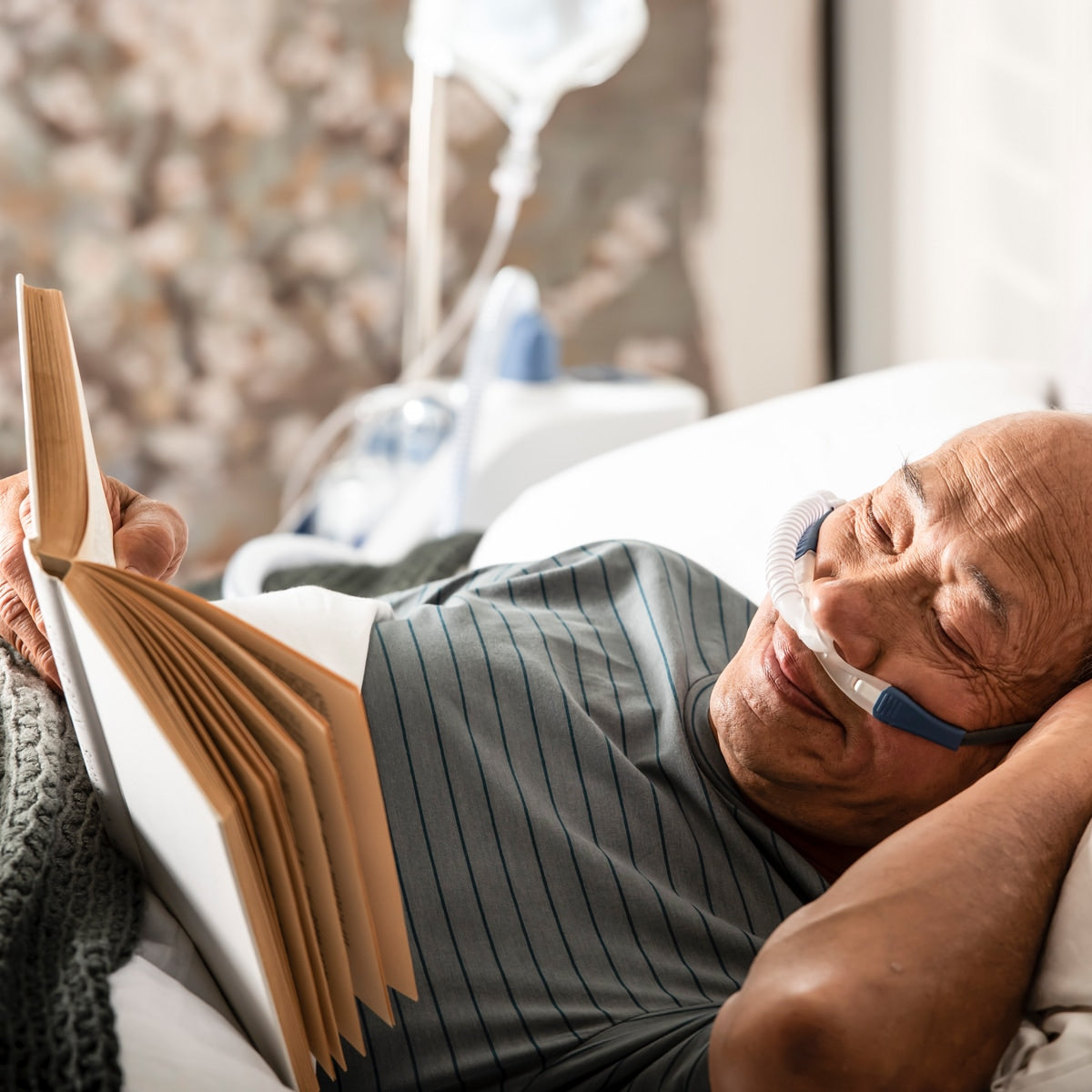 Man in bed reading and wearing myAIRVO blue cannula 