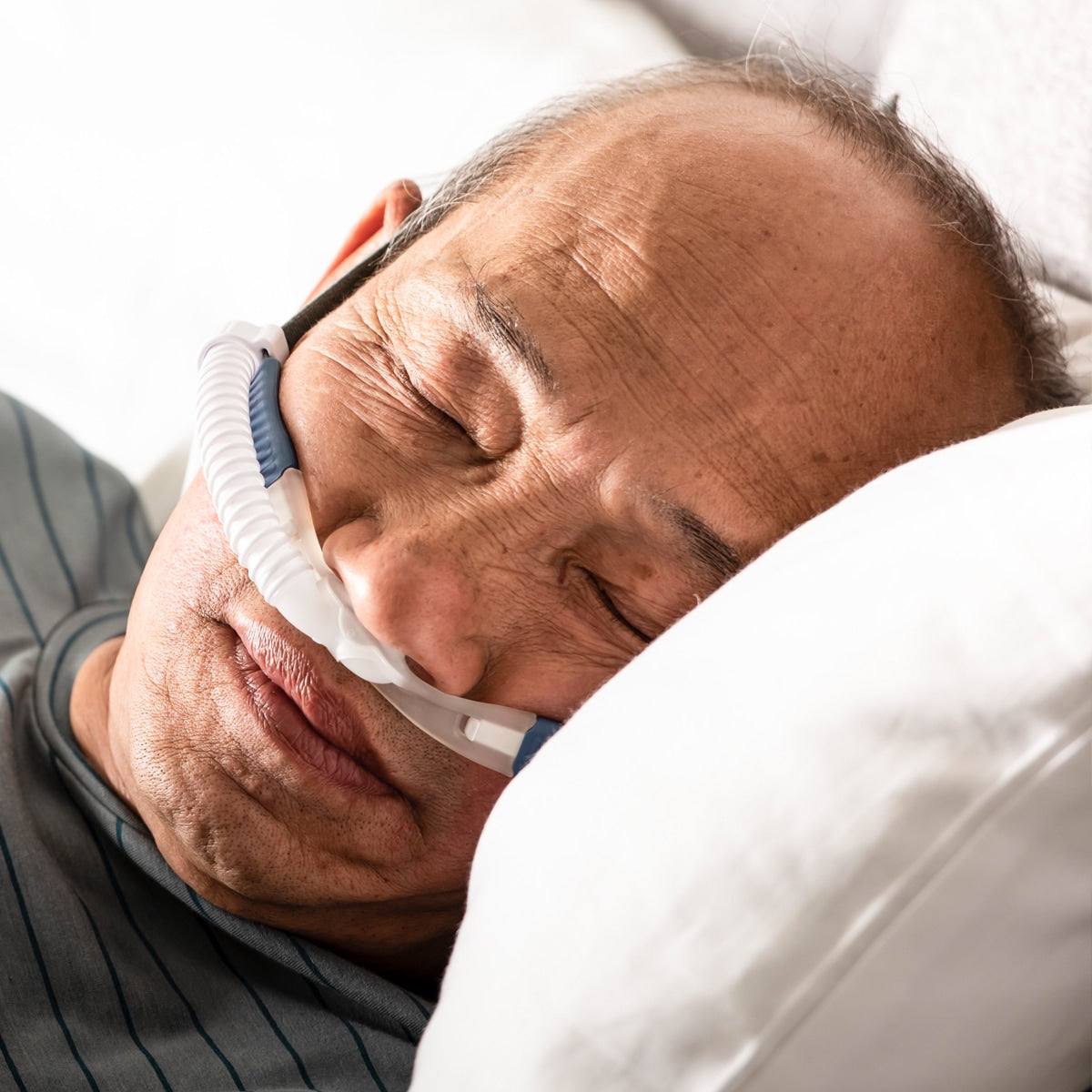 Man in bed wearing myAIRVO blue cannula 