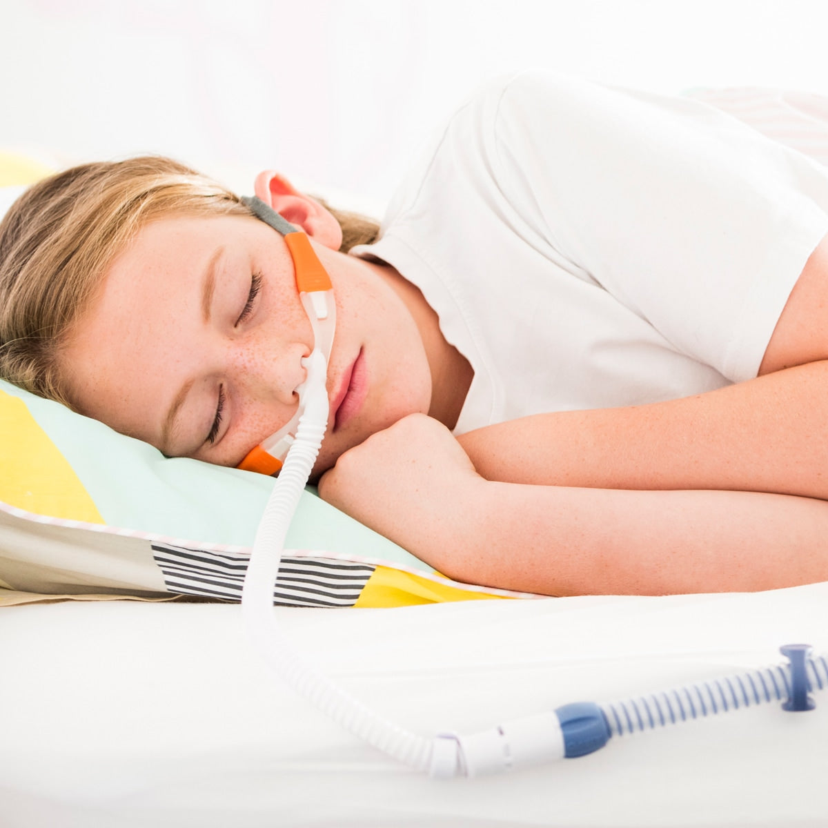 Child in bed wearing myAIRVO orange cannula 