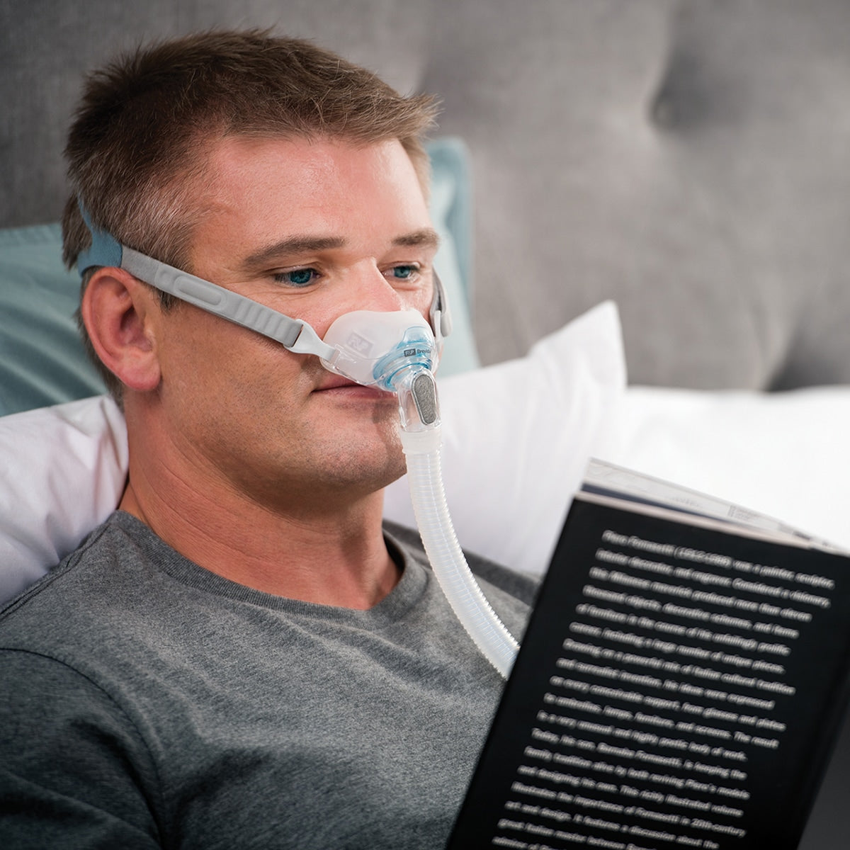 Man In Bed Reading with a Brevida Mask On 