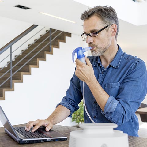 man working on computer while nebulizing with pari lc sprint