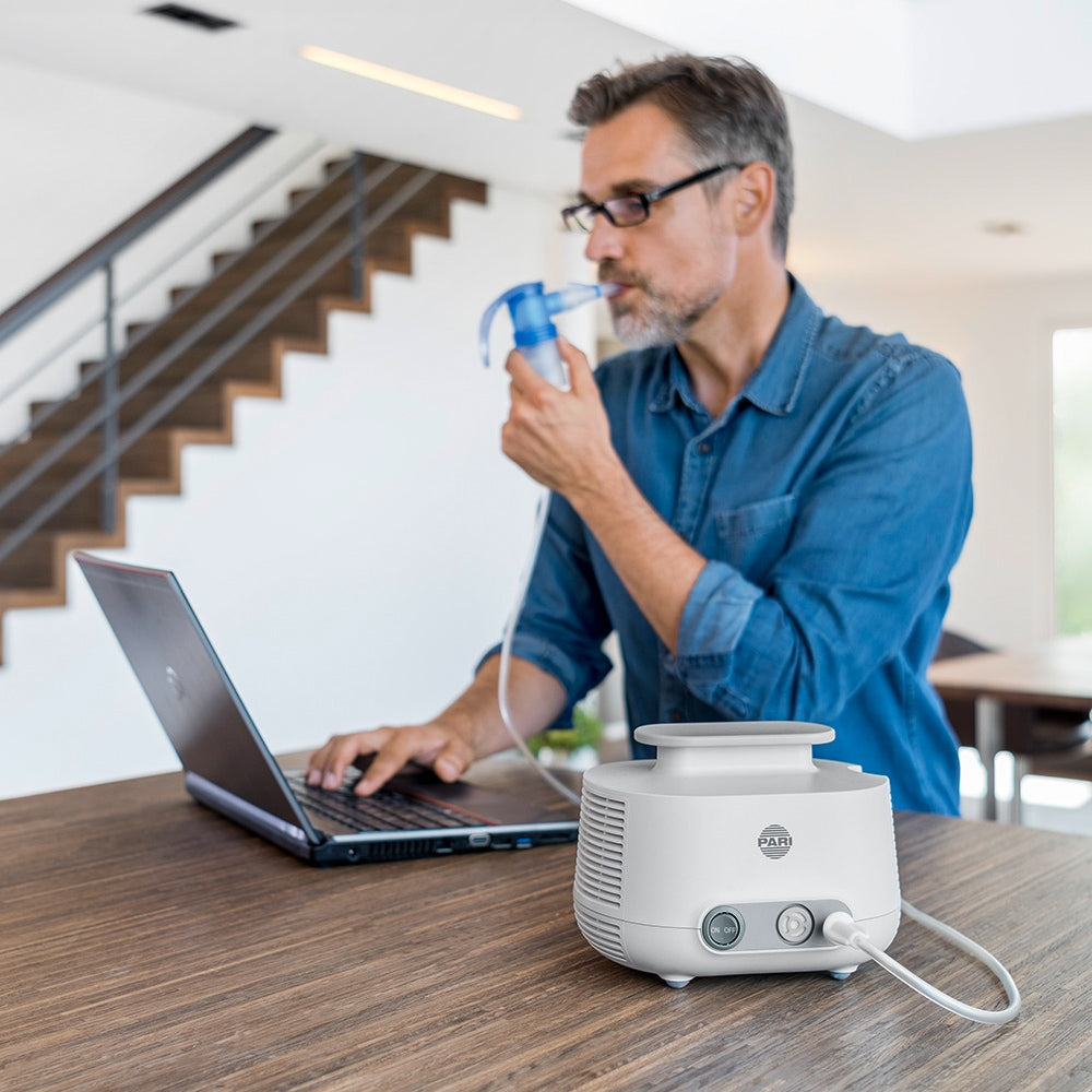 Man Working on Computer While Using a Nebulizer 