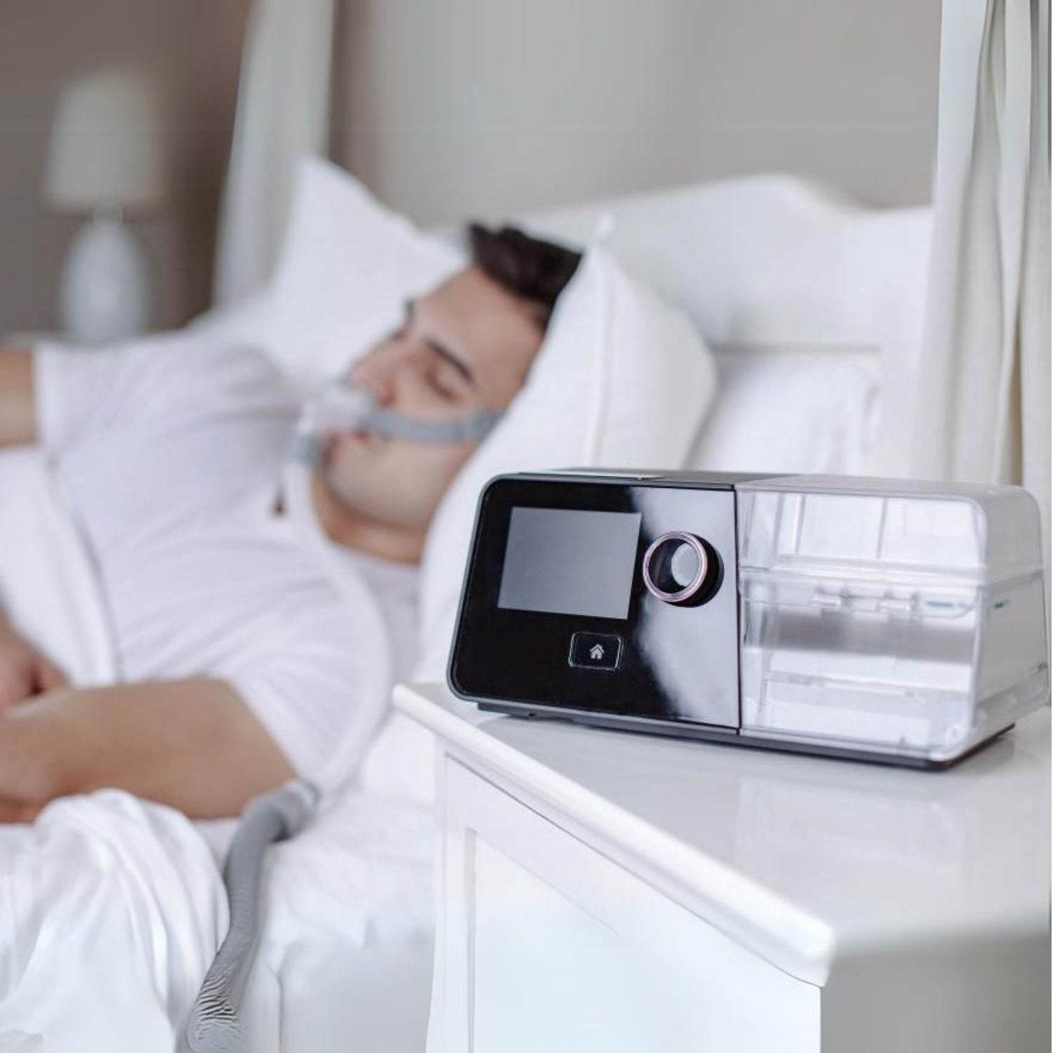 Person using a React G3X Auto CPAP machine in bed with a white background