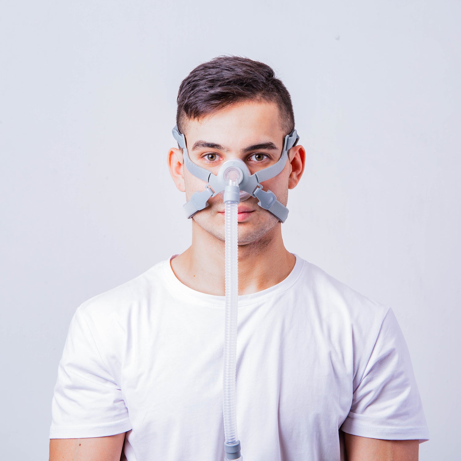 Man wearing a CPAP mask against a plain background