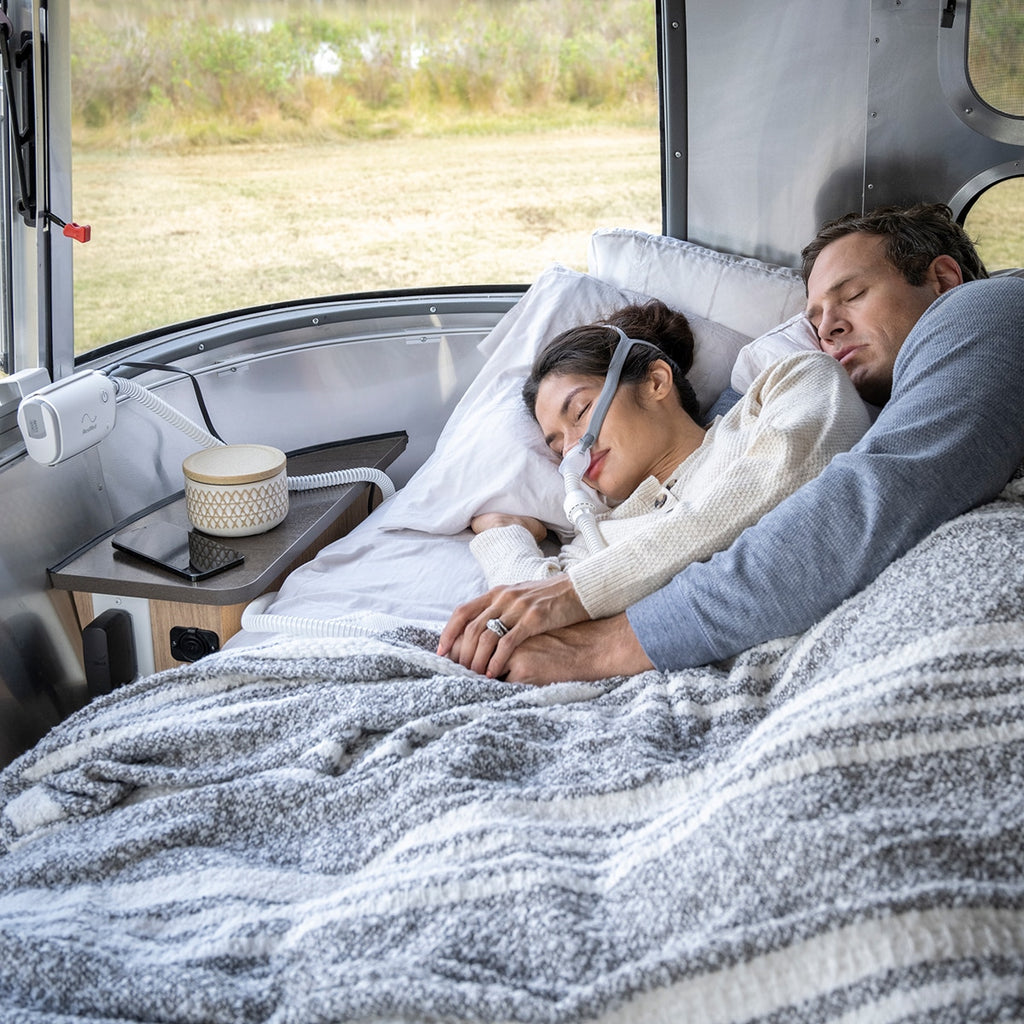 Women Sleeping with CPAP Mask on with an Airmini Auto CPAP Machine mounted to a wall in a camper 