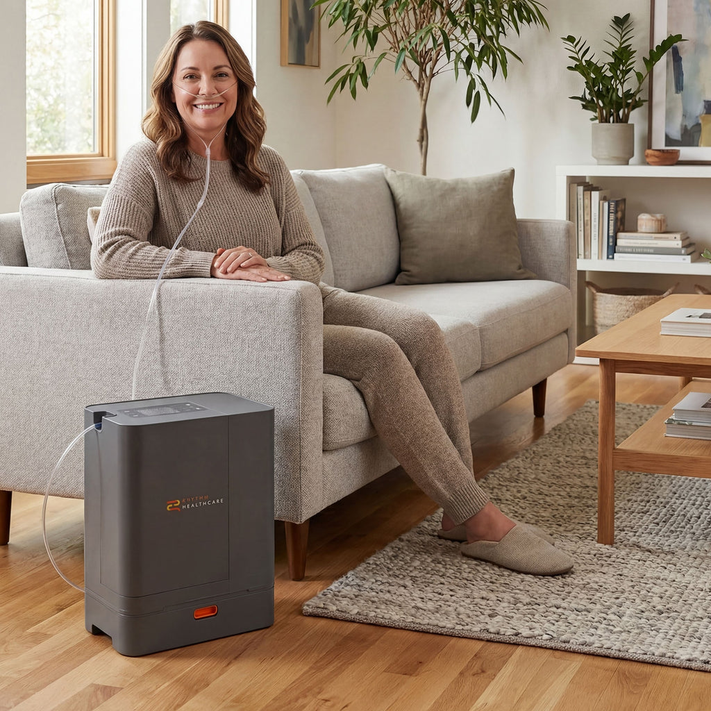 Woman sitting on a couch next to a Rhythm oxygen concentrator in a living room.