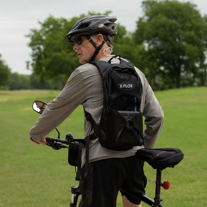 Man Riding a Bike with an X-Plor Oxygen Concentrator Backpack