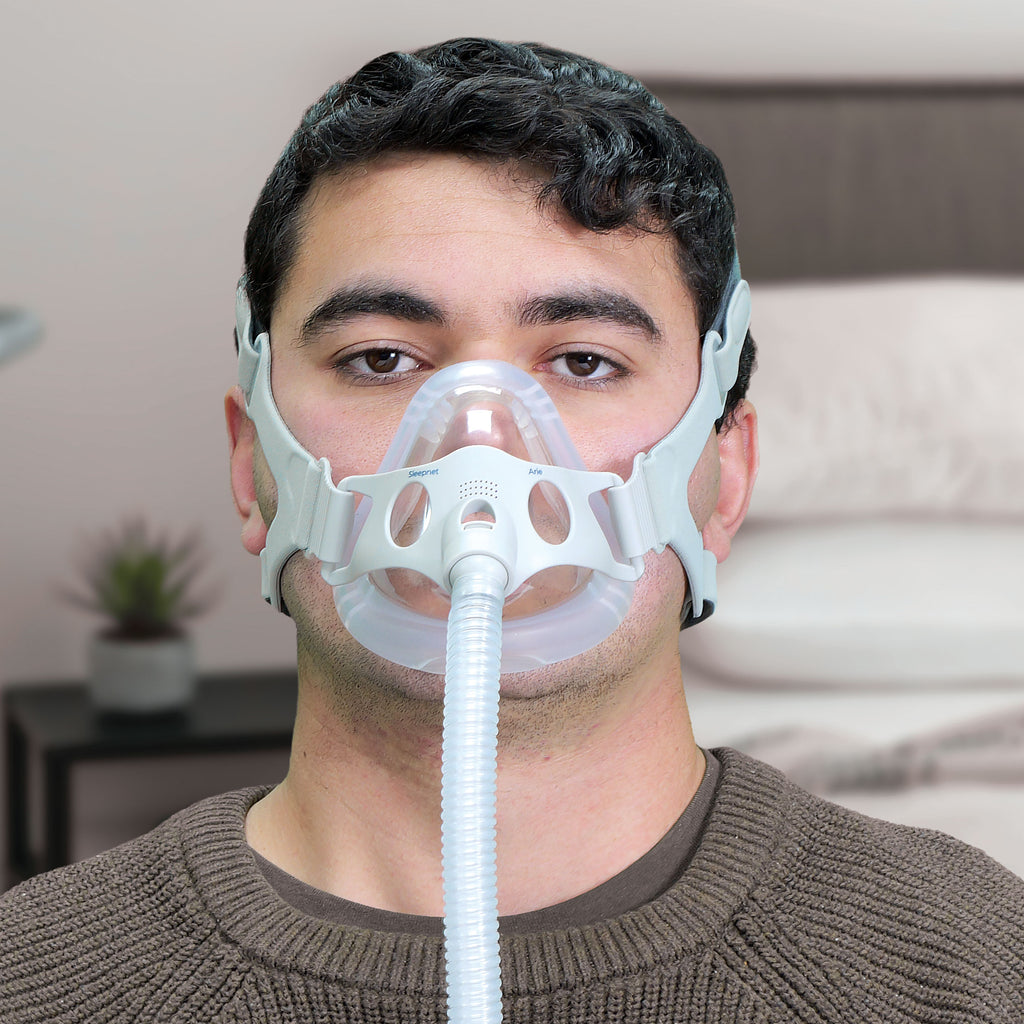Person wearing a CPAP mask with a hose in a home setting