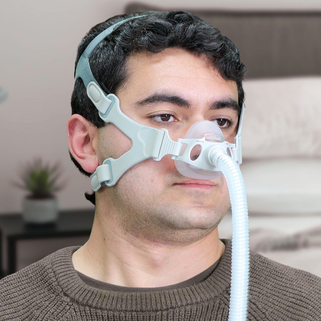 Man wearing a CPAP mask with a blurred indoor background