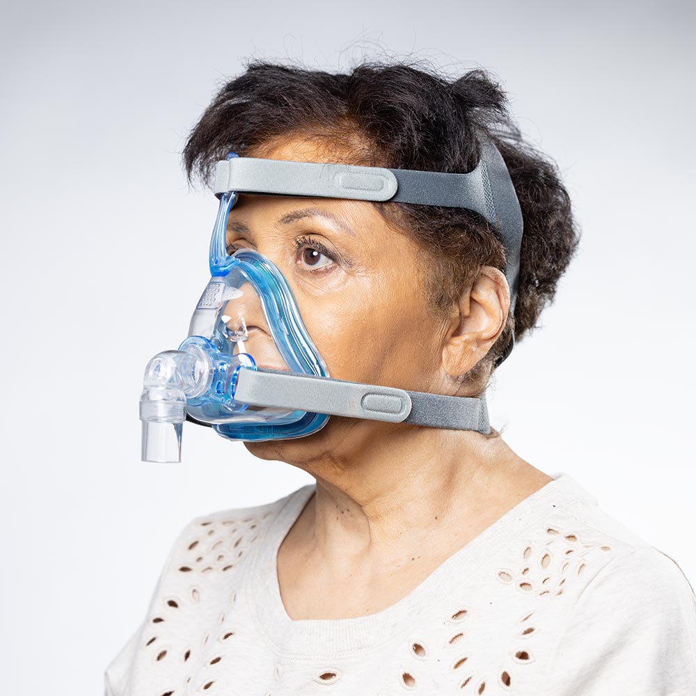 Person wearing a blue and gray CPAP mask on a white background
