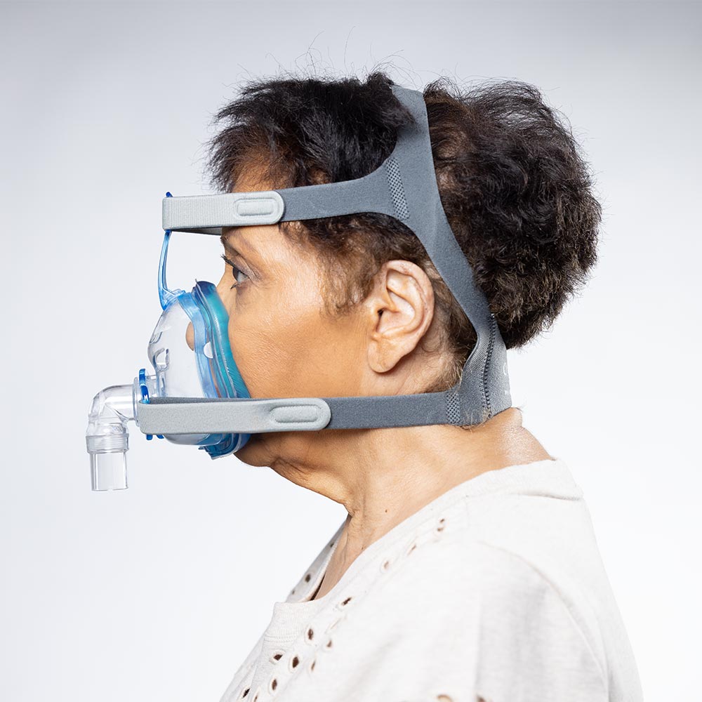 Person wearing a CPAP mask on a plain background