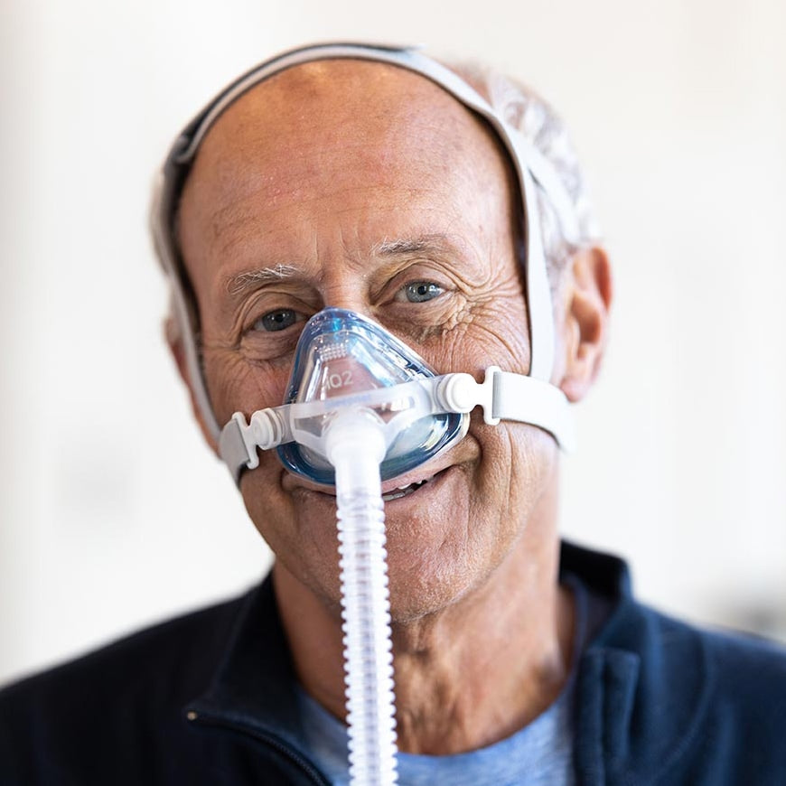 Man wearing a CPAP mask with a white background