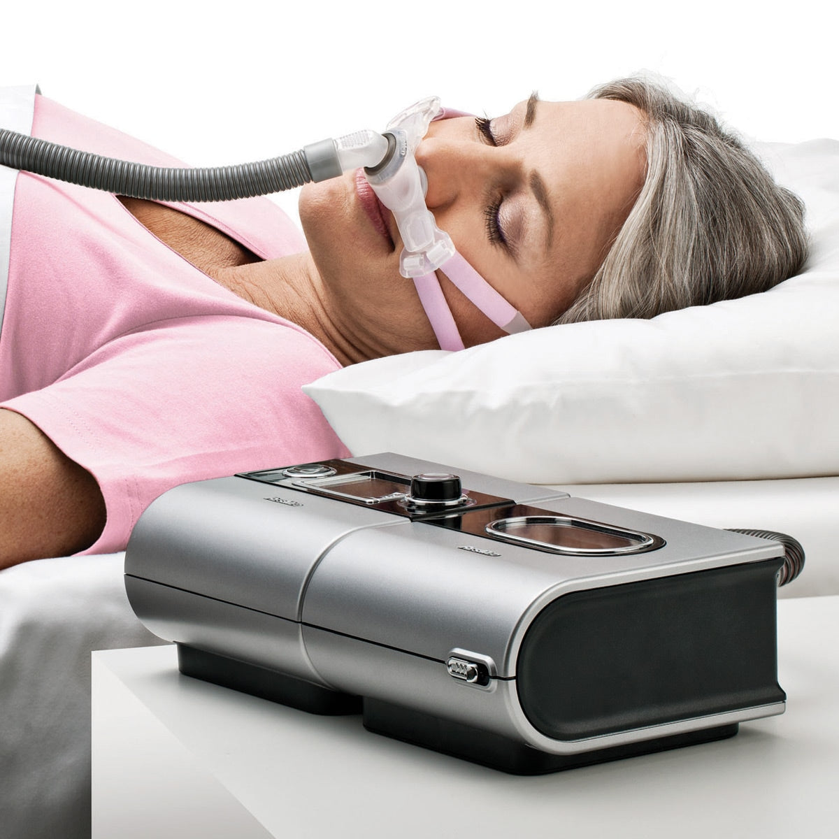 Woman using a CPAP machine to sleep, with the device in the foreground.