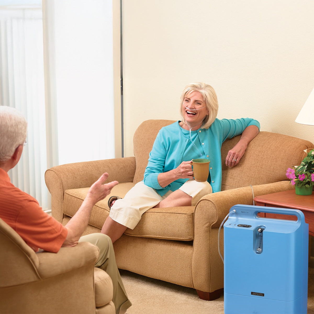 Woman sitting in a chair with a coffee mug using an EverFlo Q Concentrator 