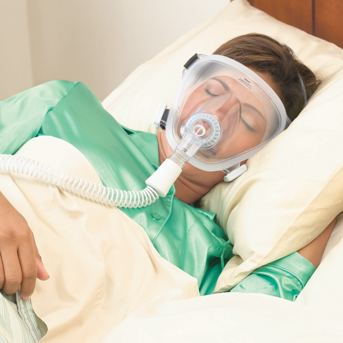 Woman in bed wearing a Fit Life Total CPAP Mask 