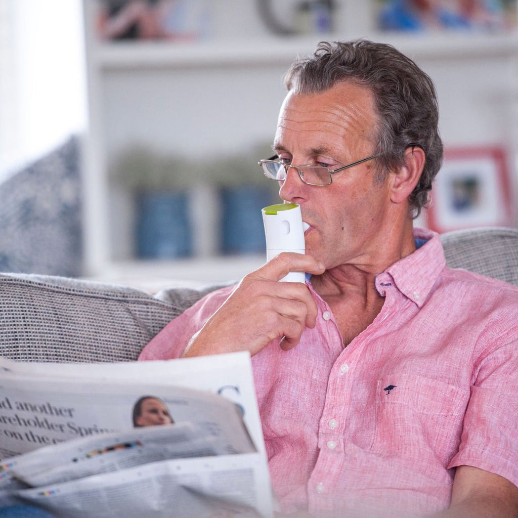 Man Reading the Newspaper while using an Innospire Go Portable Nebulizer 