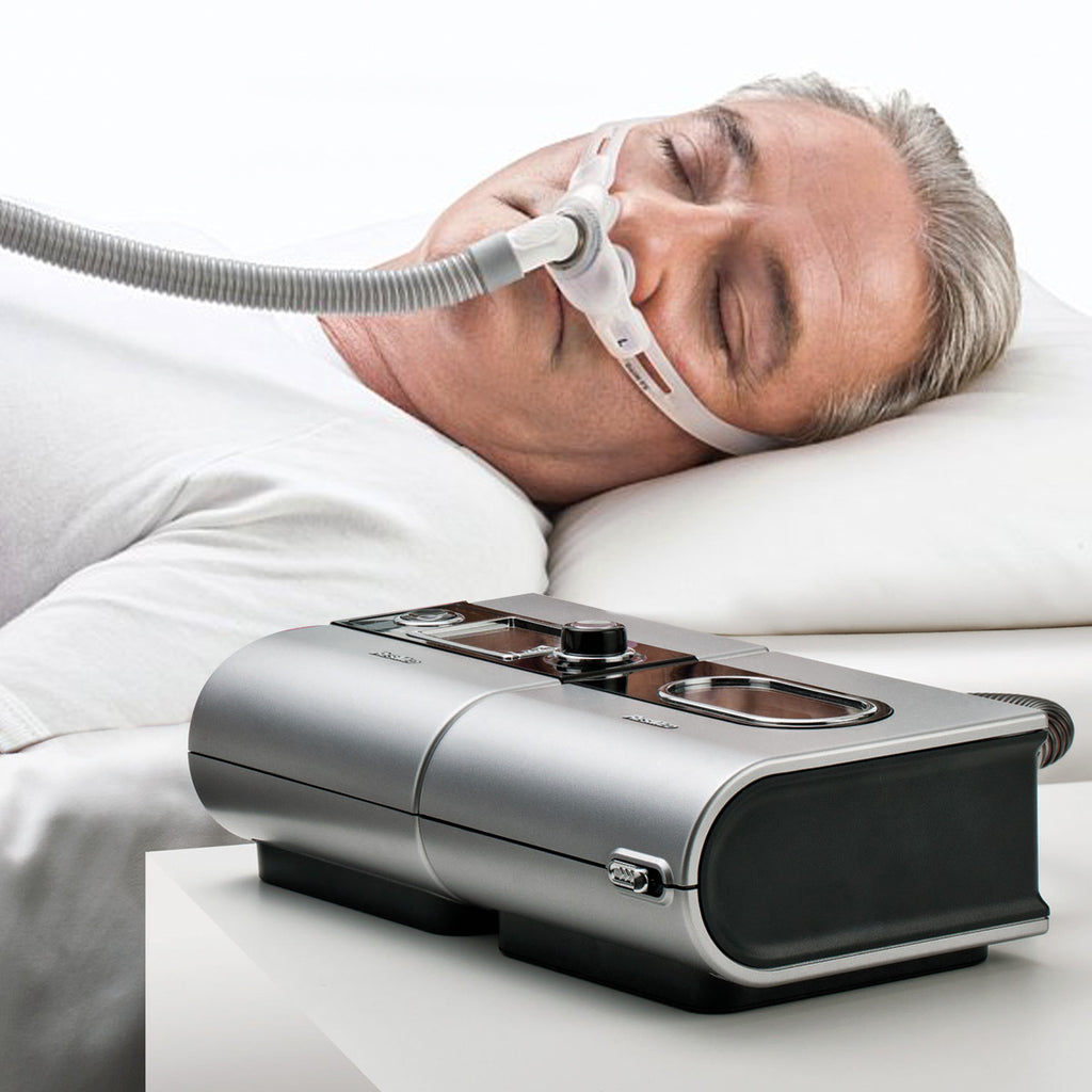 Man sleeping with Swift FX CPAP Mask on next to a CPAP 
